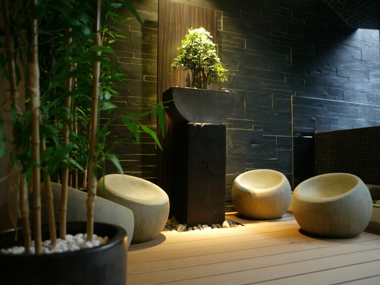 Stimmungsvoll beleuchteter Spa-Bereich mit japanischen Naturstein-Sitzen, Pflanzen und Wasserbecken – Entspannungszone im Hotel Der Heidehof Ingolstadt