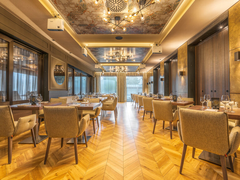 Eleganter Restaurantbereich im Hotel Der Heidehof mit gedeckten Tischen, stilvollen Holzfußboden und moderner Deckenbeleuchtung